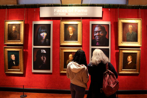 Two visitors look at a portraits hung in the gallery