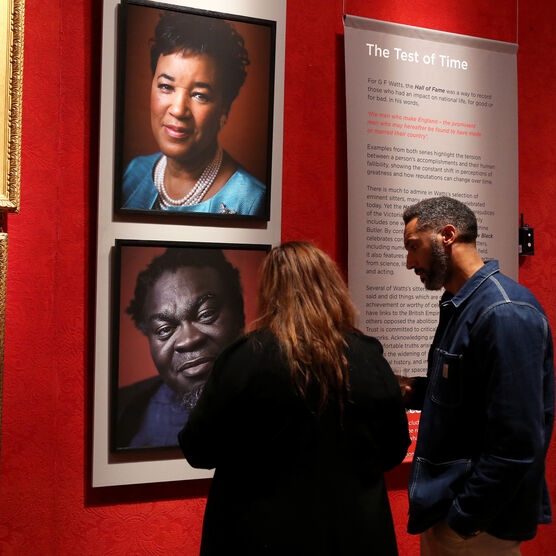 Two visitors look at Faces of Fame exhibition in gallery
