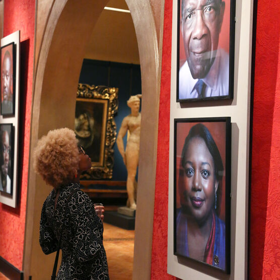 Women looks at photographic portraits on wall