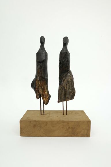 Two pieces of driftwood mounted on wooden pedestal cut into rough shapes of figures