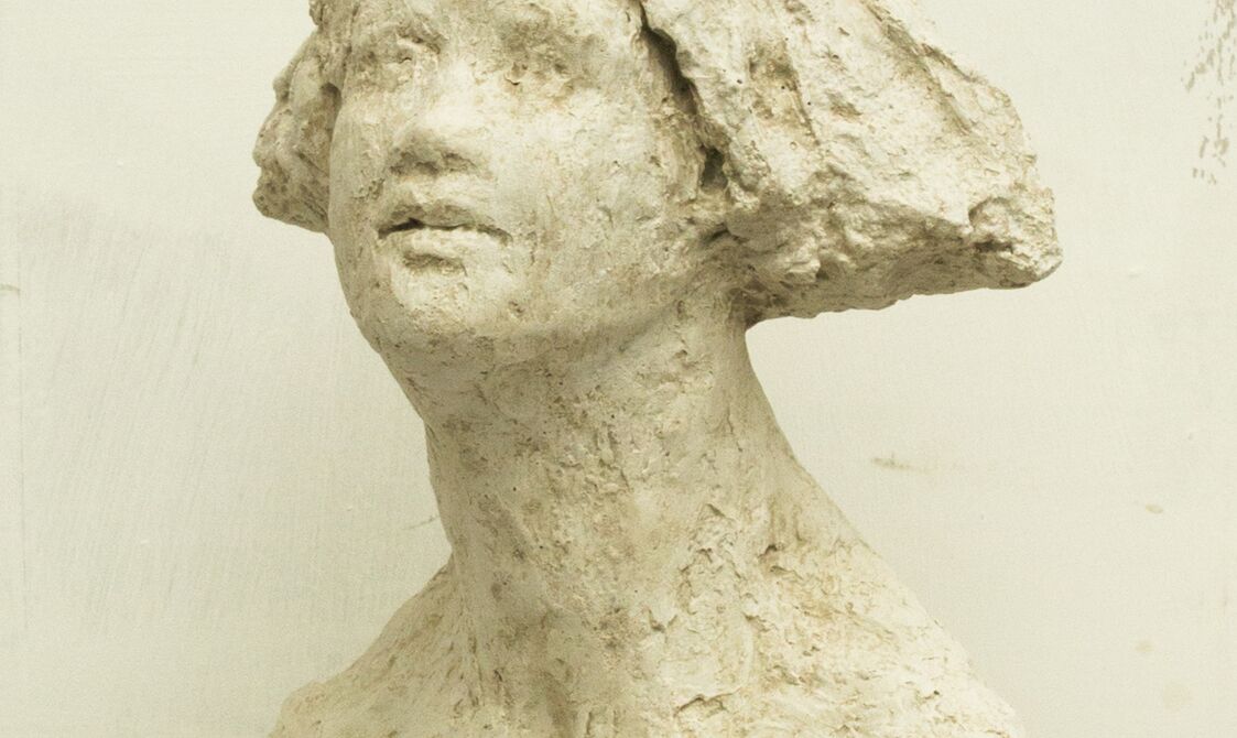 A rough sculpture bust of a woman with a bobbed haircut