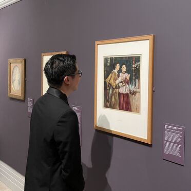 A man stands in front of a painting at the exhibition Pre-Raphaelite Treasures
