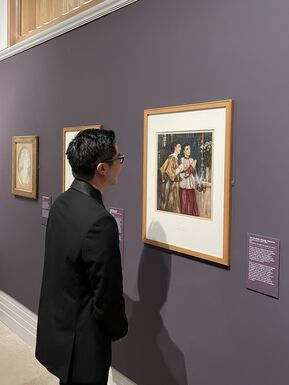A man stands in front of a painting at the exhibition Pre-Raphaelite Treasures