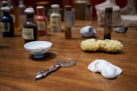 Close-up photo of a magnifying glass, a natural sponge and small tubes filled with dirt