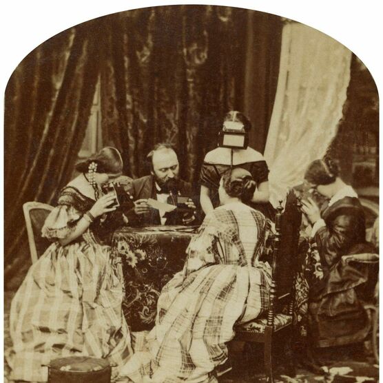 Stereo photograph of a Victorian family looking at stereo photographs and stereoscopes