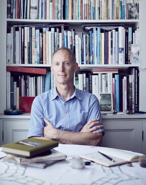 Portrait of a man in a blue shirt sitting with his arms crossed