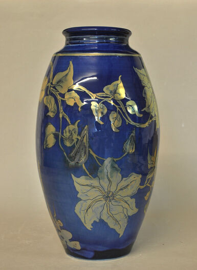 Tall blue lustreware vase with goldy-silver coloured clematis flowers around it
