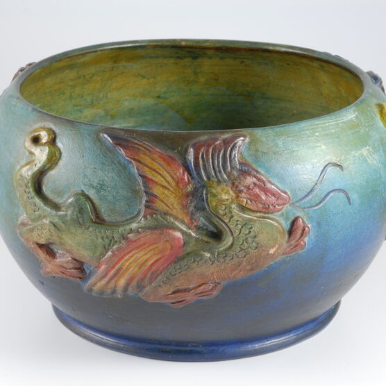 Blue and green bowl with yellow inside decorated with a red and green dragon on the outside