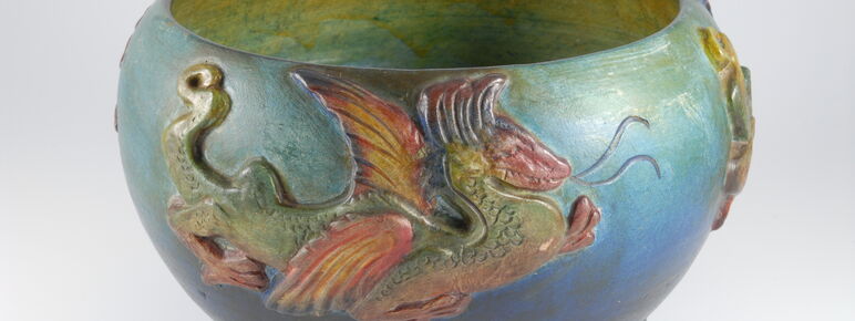 Blue and green bowl with yellow inside decorated with a red and green dragon on the outside