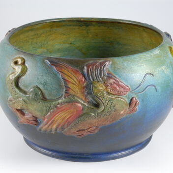 Blue and green bowl with yellow inside decorated with a red and green dragon on the outside