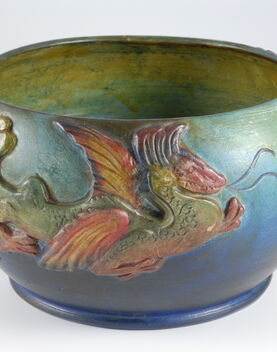Blue and green bowl with yellow inside decorated with a red and green dragon on the outside
