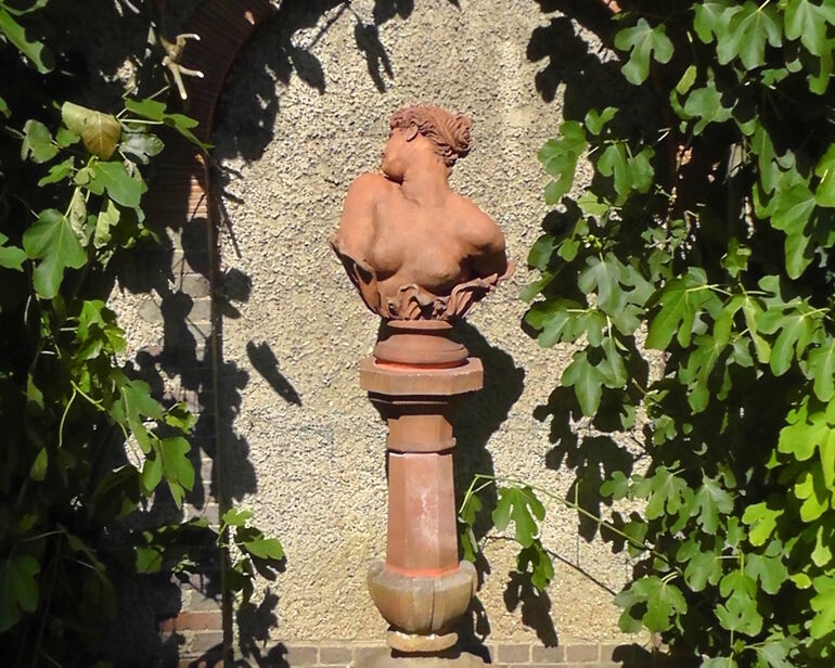 Terracotta version of Clytie on a terracotta plinth in the sunken garden outside Watts Gallery
