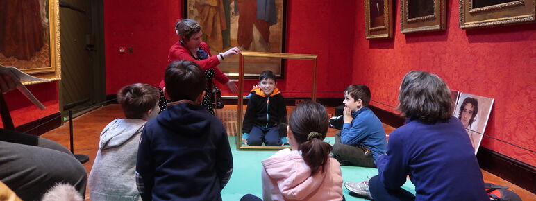 A group of families sit in the gallery listening to stories
