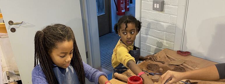 A young girl and young boy make using clay