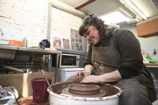 Ashleigh throws a clay dish on the pottery wheel