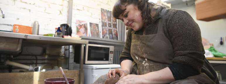 Ashleigh throws a clay dish on the pottery wheel