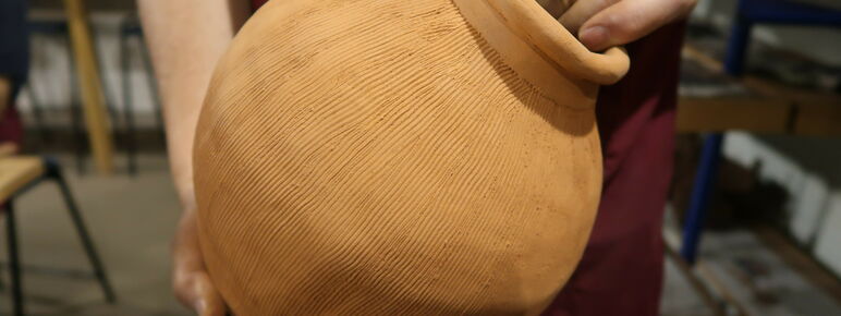 Someone holds a large round clay pot