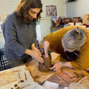 Two women working together on a ceramic piece of art