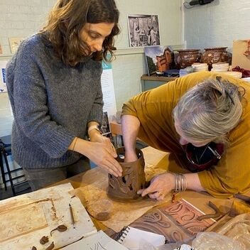 Two women working together on a ceramic piece of art