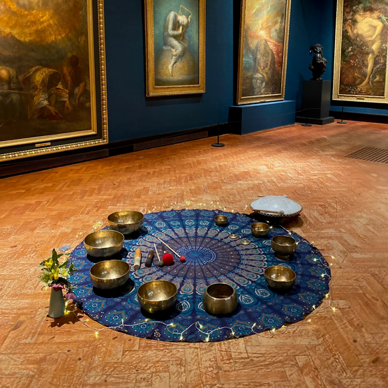 A set up on the floor in the historic galleries of a rug, candles and lights
