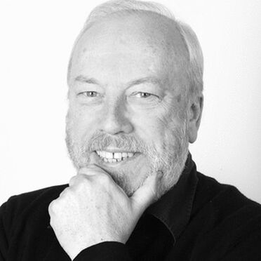 A black and white portrait of Peter Brookes smiling with my hand resting on his chin.