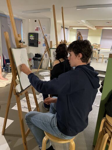 A photo of a young boy sitting at an easel drawing