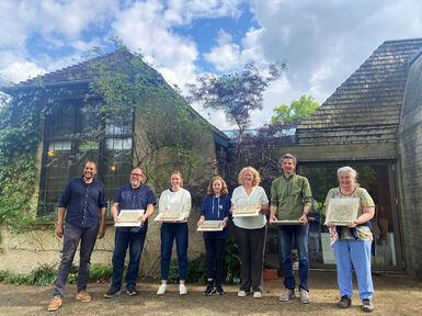 A group of seven stand in front of the Pottery Building with their clay creations