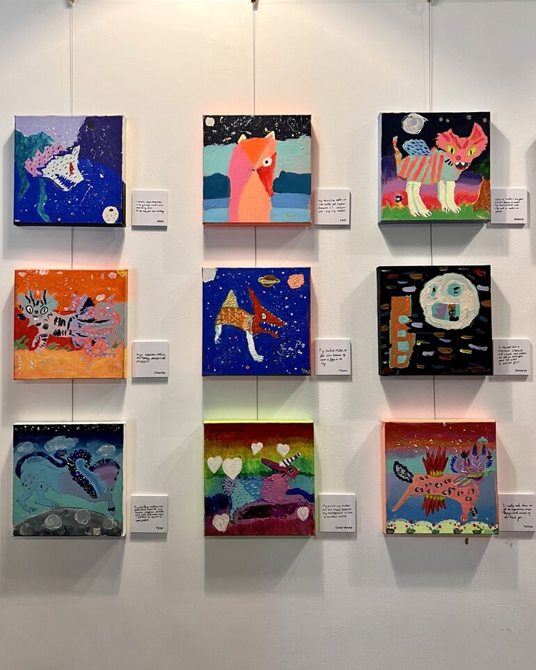 Square paintings by children hung on wall