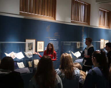 Photo inside an exhibition at Watts Gallery where a curator is giving a talk to a group of secondary school students