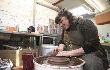 Ashleigh throws a clay dish on the pottery wheel