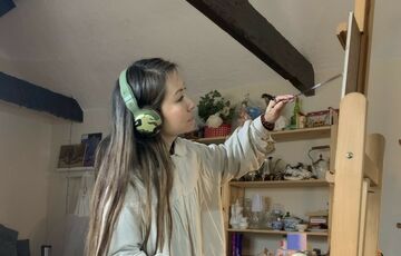 Sarah paints on an easel