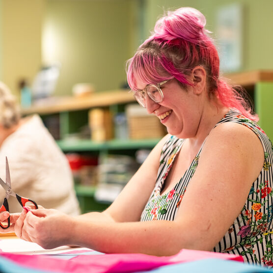 Community participant, a lady with pink hair, creating art in a session