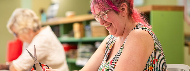 Community participant, a lady with pink hair, creating art in a session