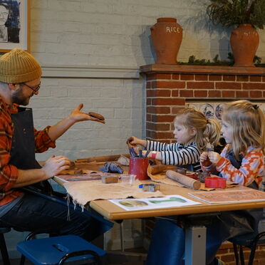 Father with two daughters sitting at a table doing pottery