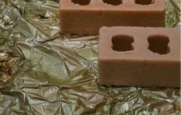 Photo of some bricks laid on the ground on top of green plastic tarp