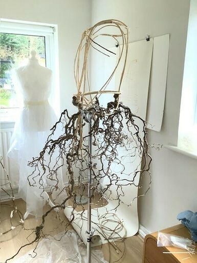 Photo of a wire mannequin with a skirt accessory wrapped around it. The accessory resembles a bunch of twigs.