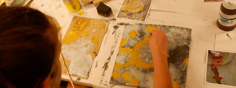 A girl adds paint to a photograph of some flowers