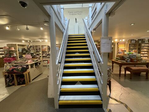 Stairs up to gallery, there are wooden handrails and grips