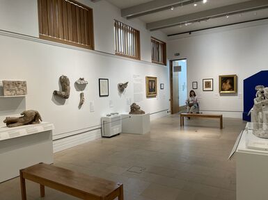 Temporary exhibition space set up for A Fragmented Legacy, the walls are white and pieces of sculpture and artwork line the walls