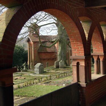 Terracotta corridor with arches, the chapel stands in the background