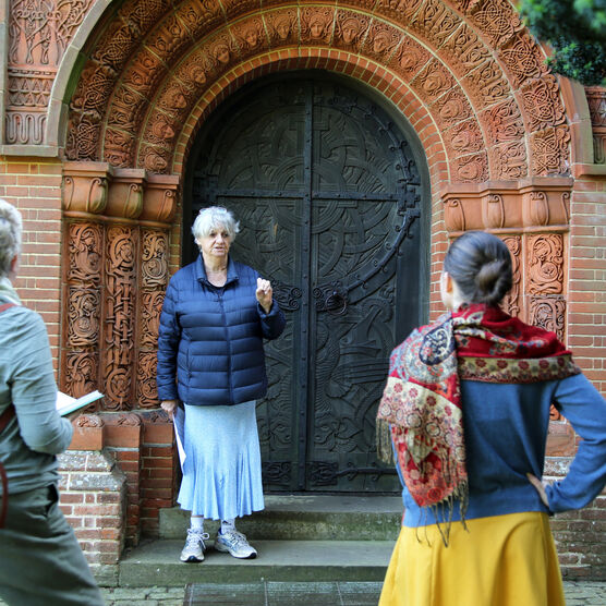 A volunteer stands in front of a group by the highly-decorated Watts Chapel black door