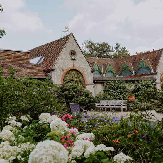 Exterior of Watts Gallery - Artists' Village with summer flowers in the foreground
