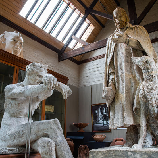 Plaster model of a women in foreground, with Alfred Lord Tennyson statue in background, featuring a man and dog