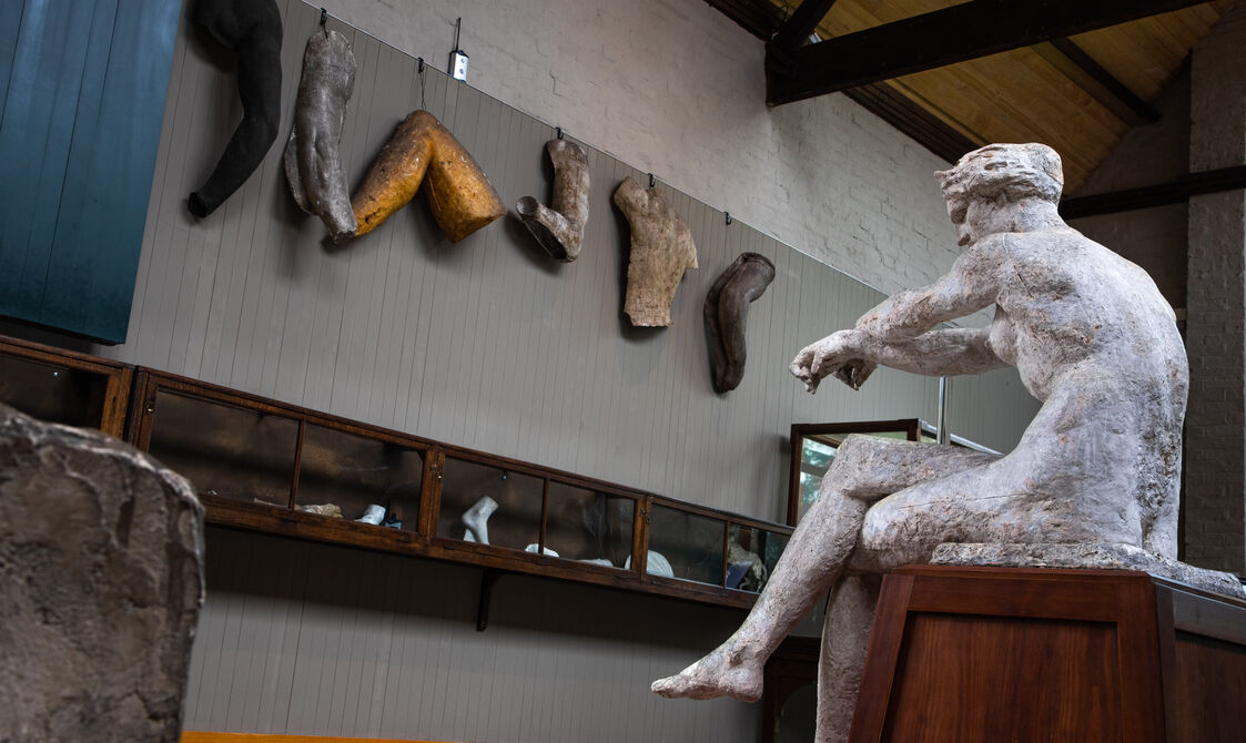 A plaster model of a women sits on a wooden plinth
