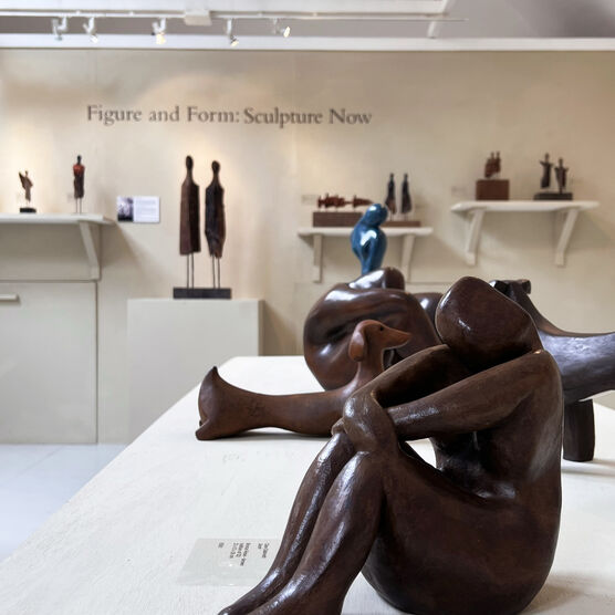 Wooden sculpture of women sat down with knees up