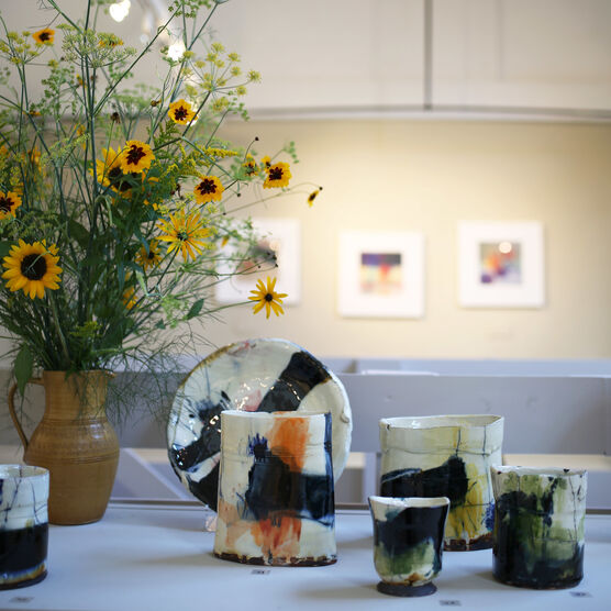 White vases with colourful patterns on a table with a vase of yellow flowers
