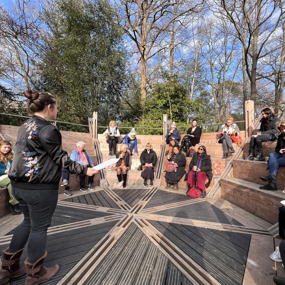 A group of people sit on the wooden round amphitheatre