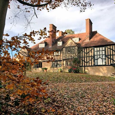 Panelled house with trees and autumn leaves