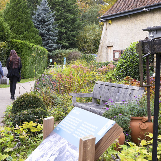 Two visitors walk along the path with flower beds next to them