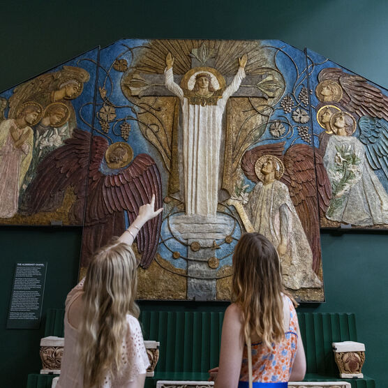 Two visitors point at decorative panel